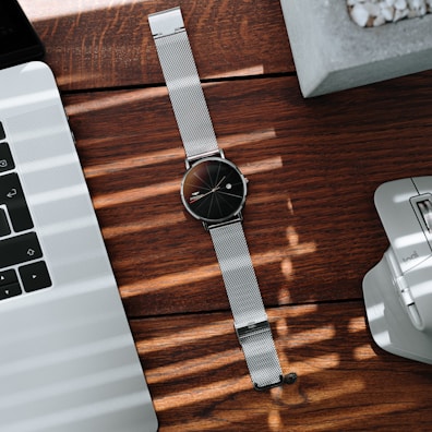 Lunamesh watch with a white dial and silver mesh strap catching sunlight on a city street.