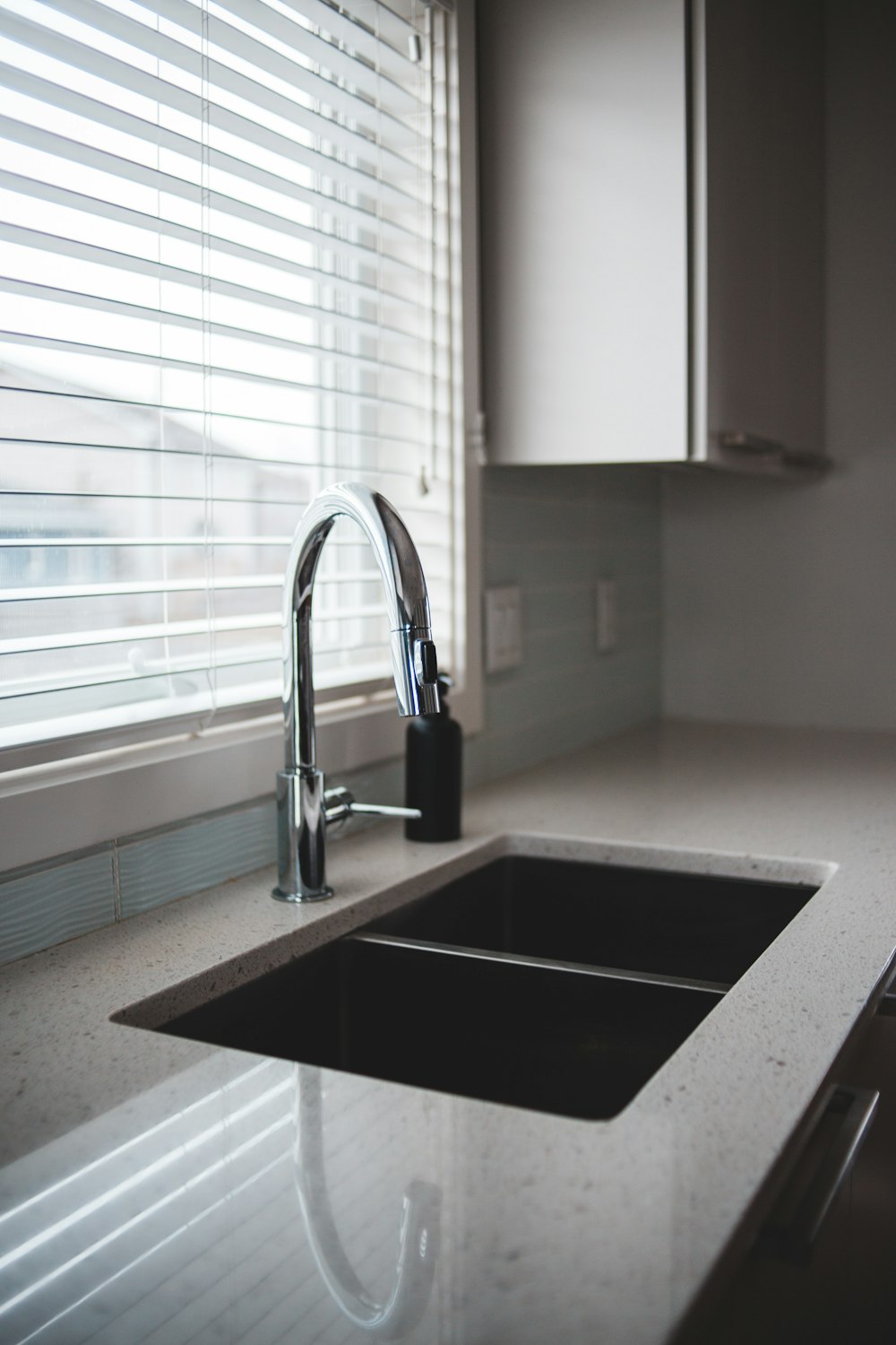 stainless steel faucet near white window blinds