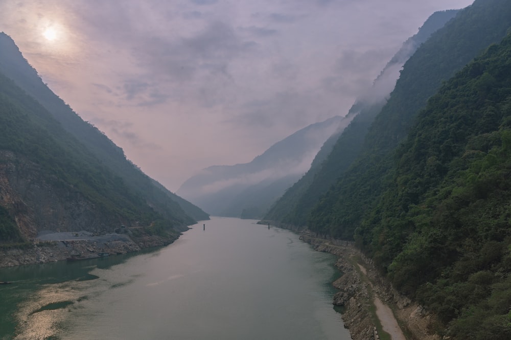 green mountains beside river under cloudy sky during daytime