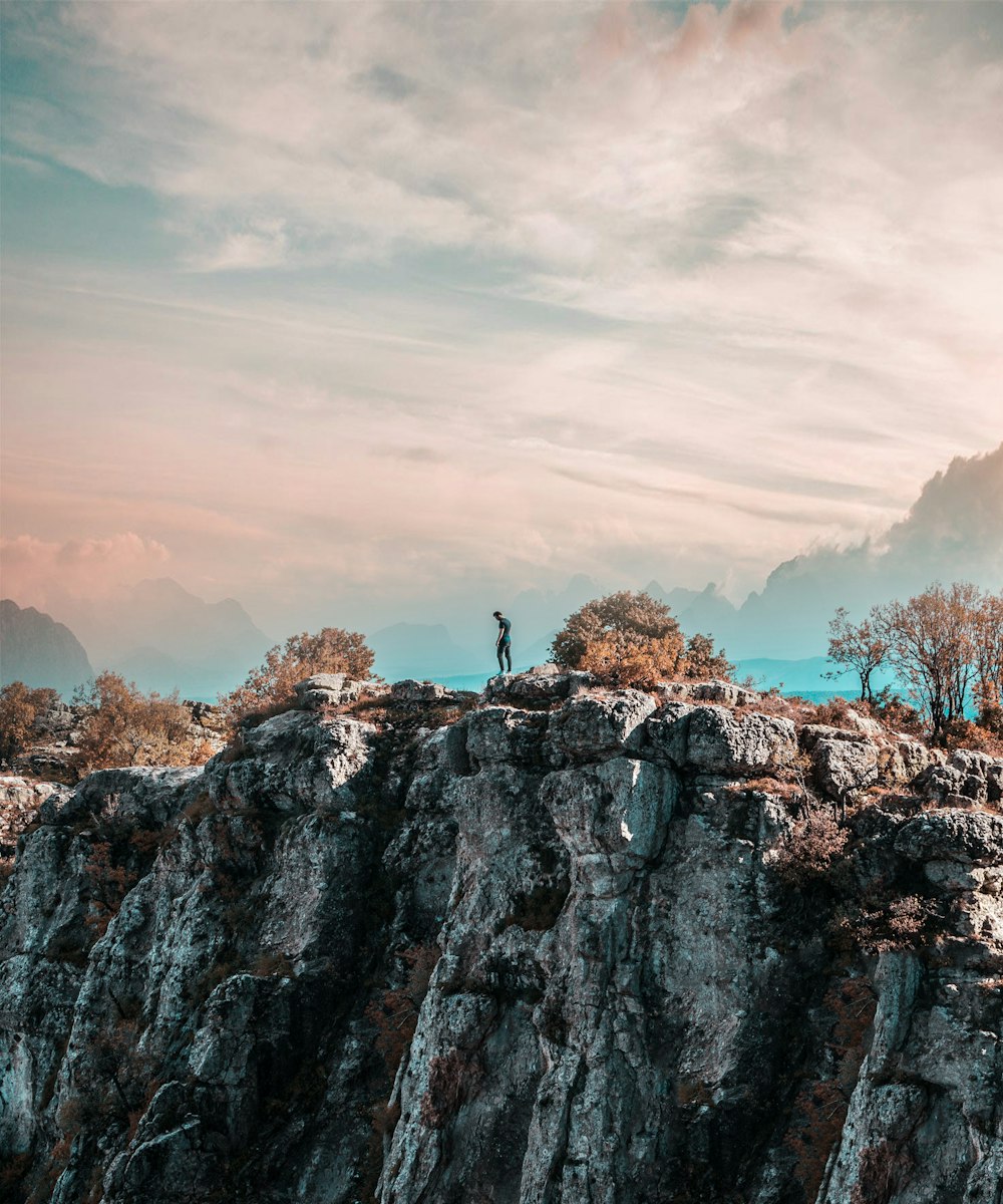 person standing on rocky mountain during daytime