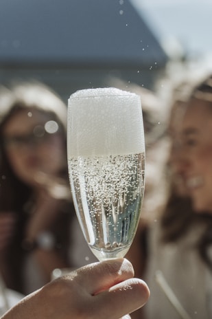 Close-up of a hostess holding a flute of champagne with a soft, inviting smile.