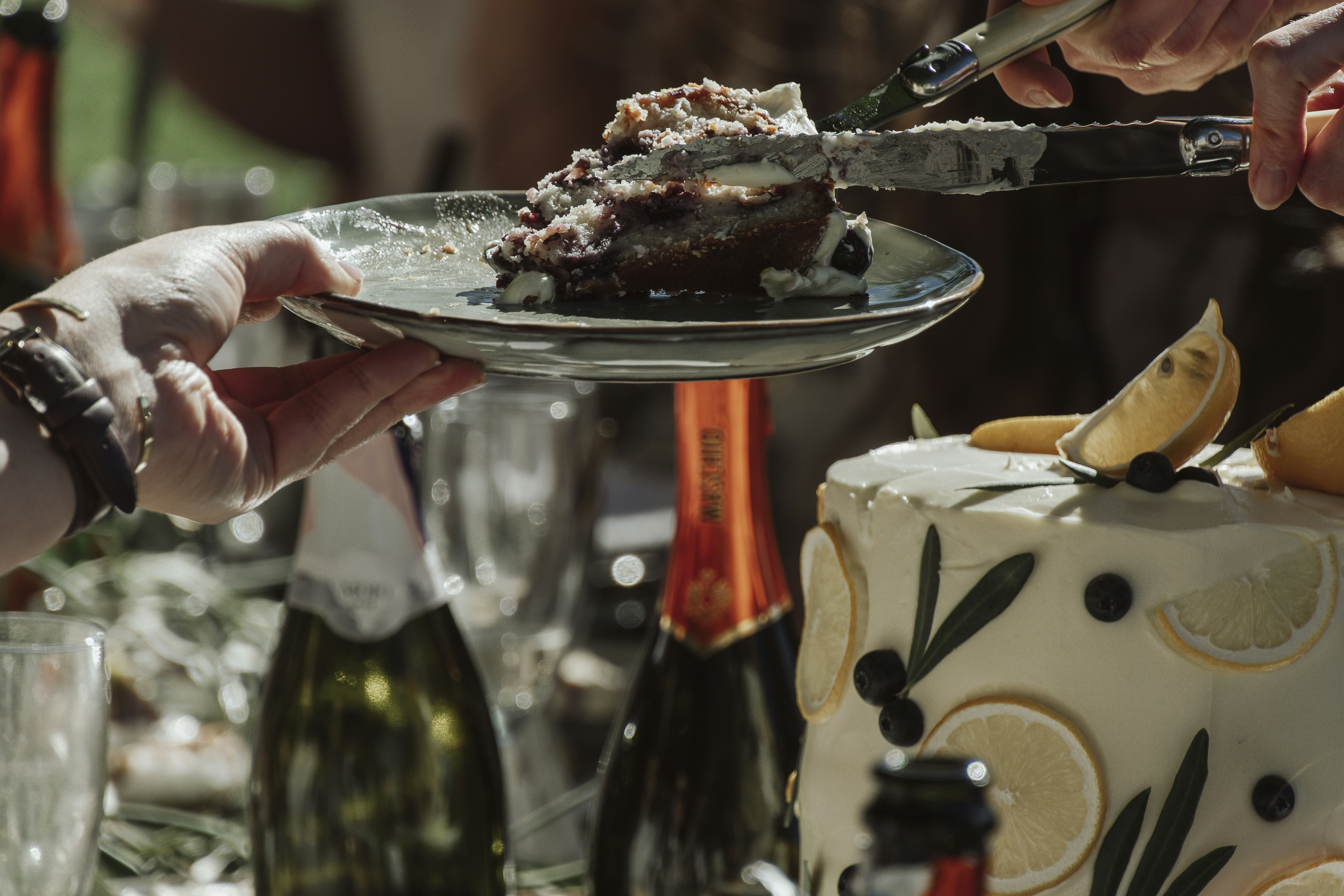 Server lifting a slice of cake beside champagne glasses