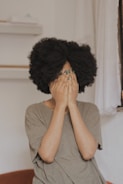 woman in gray t-shirt covering face with both hands