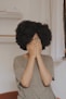 woman in gray t-shirt covering face with both hands
