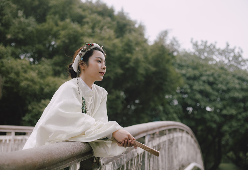 woman in white long sleeve dress sitting on brown wooden chair