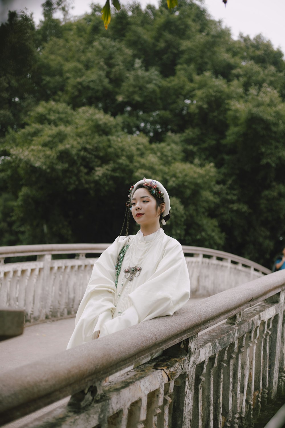 woman in white long sleeve shirt and white floral hijab standing on bridge during daytime