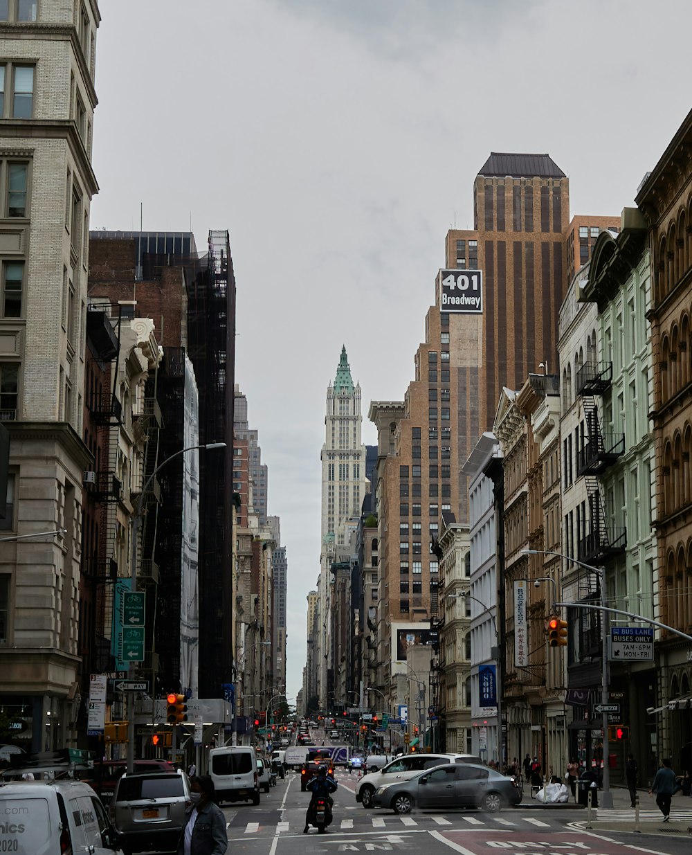 cars parked on side of the road in between high rise buildings during daytime