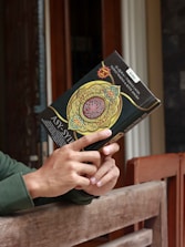 A serene image of a person reflecting quietly with a Quran and notebook nearby.