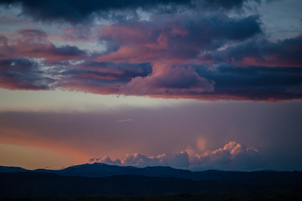 silhouette of mountains under cloudy sky during sunset