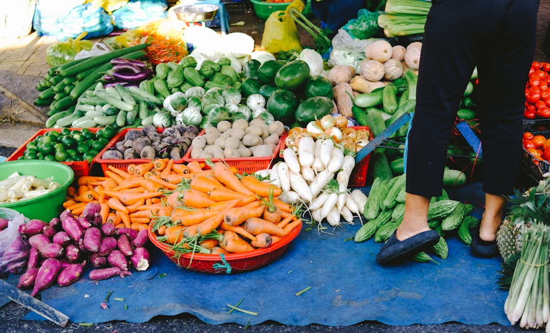 person holding red plastic plate with vegetables