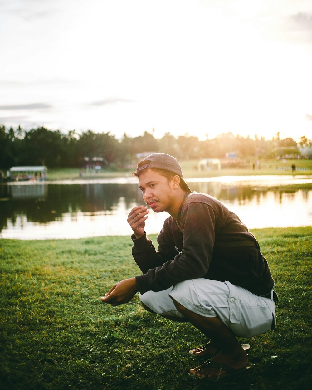 man in black long sleeve shirt and gray pants sitting on green grass field near body