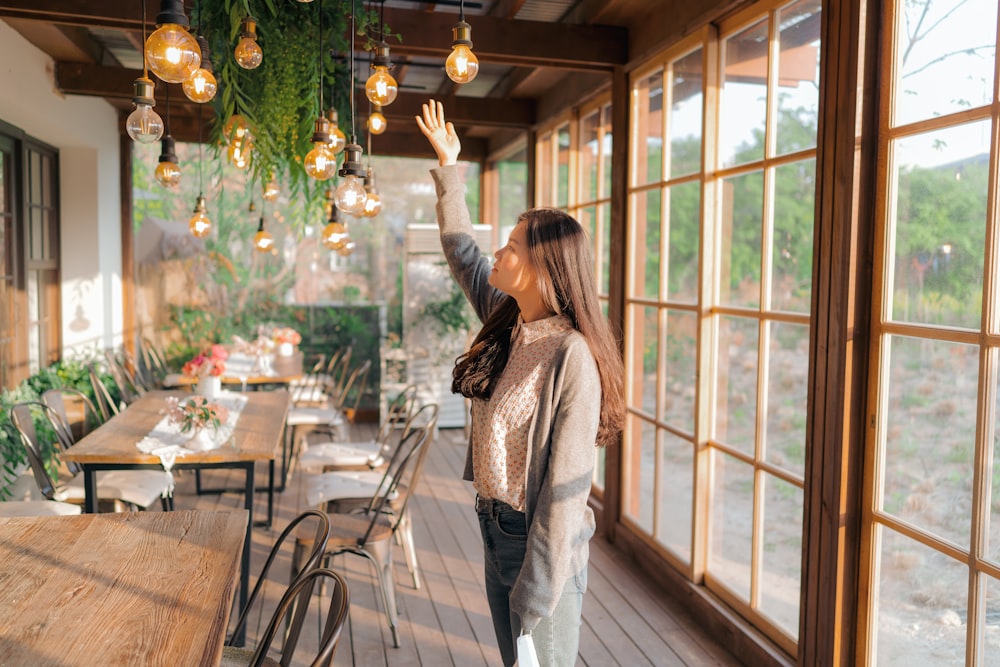 woman in white long sleeve shirt and gray pants standing near glass window