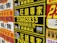 A collection of colorful advertisement posters displayed on a wall, featuring large, bold text in various fonts, primarily in Chinese characters, with some English text. Yellow, black, and red are the prominent color schemes used in the posters.