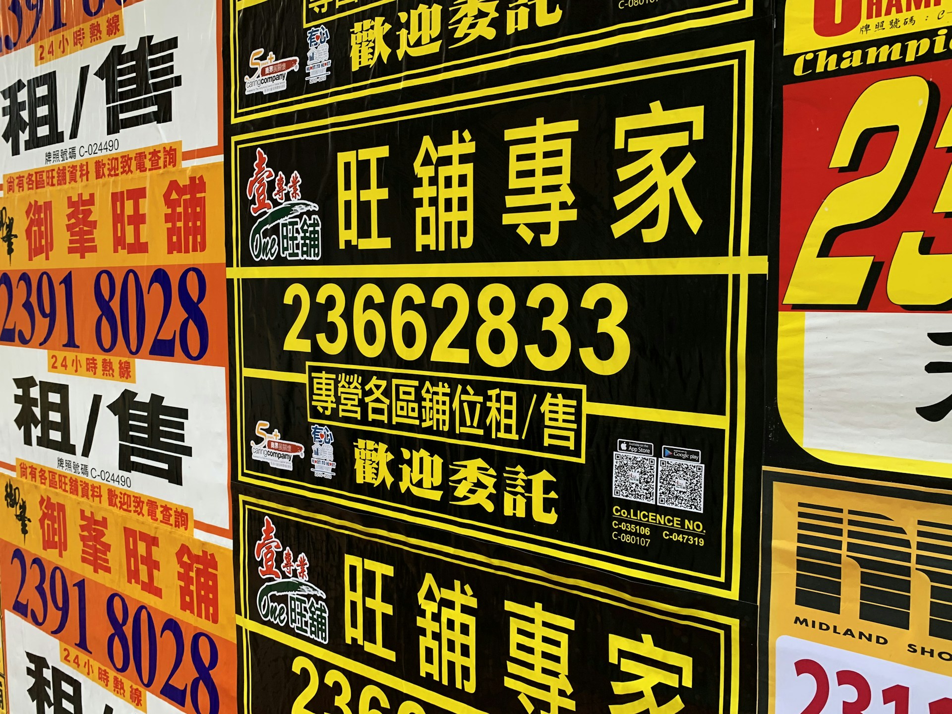A collection of colorful advertisement posters displayed on a wall, featuring large, bold text in various fonts, primarily in Chinese characters, with some English text. Yellow, black, and red are the prominent color schemes used in the posters.