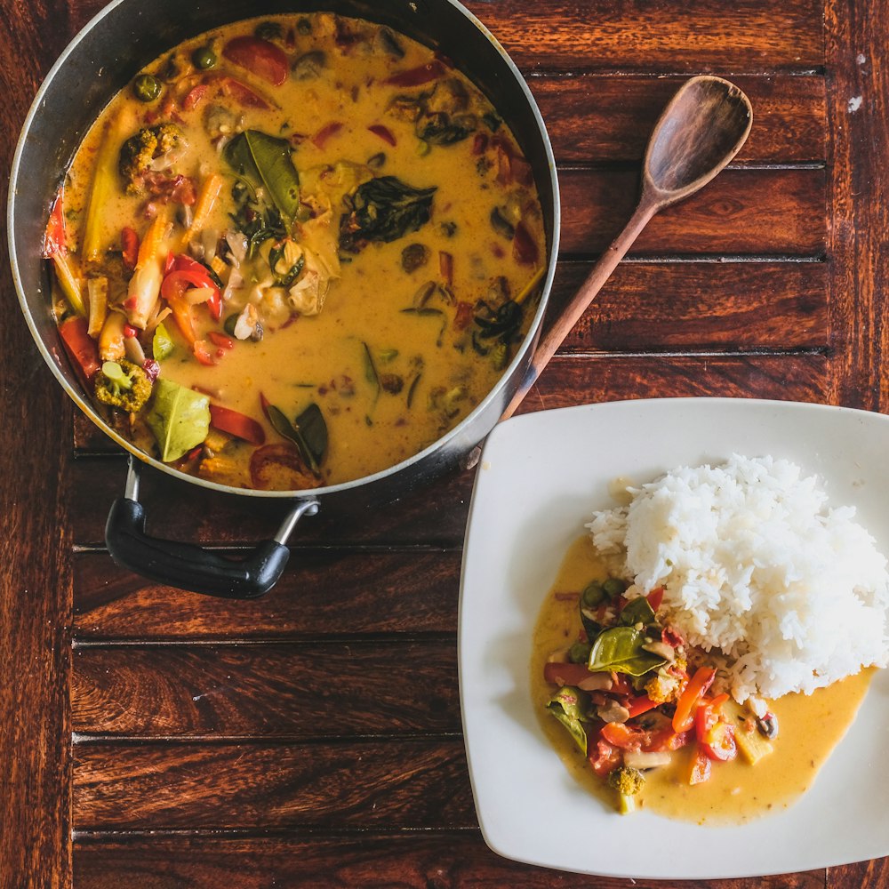 soupe aux légumes sur bol en céramique blanche à côté d’une cuillère en acier inoxydable