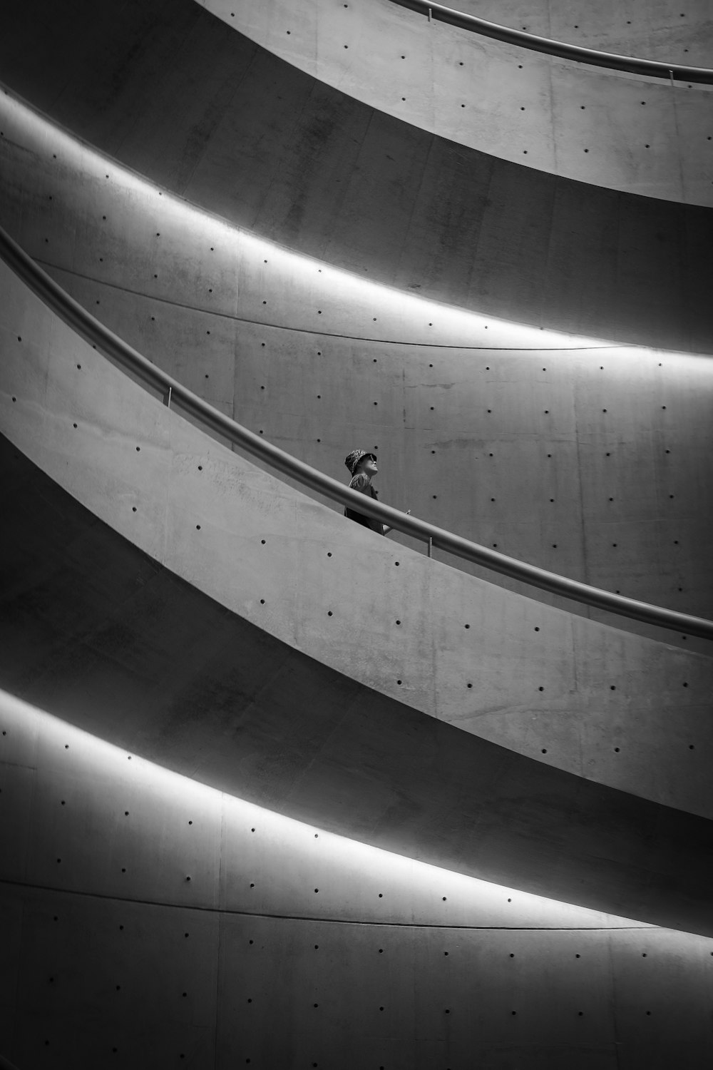 grayscale photo of man walking on spiral staircase