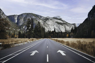 gray concrete road near mountain during daytime