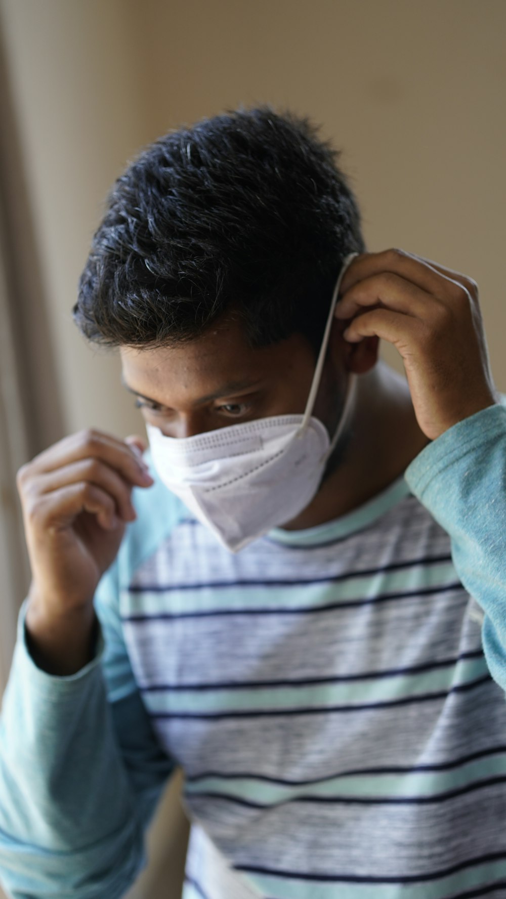 man in blue and white stripe crew neck shirt holding white face mask