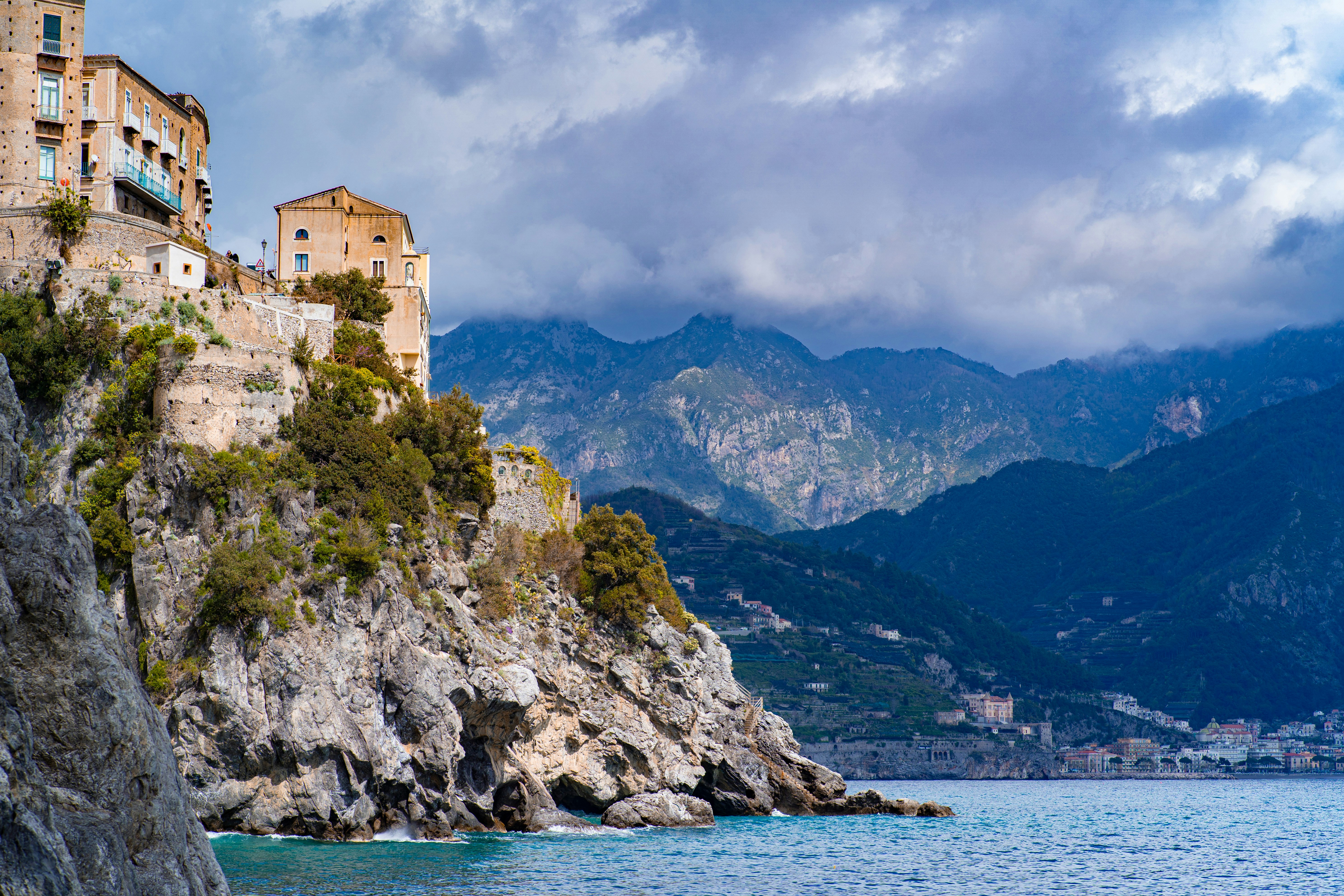 edificio in cemento marrone vicino allo specchio d'acqua sotto il cielo nuvoloso durante il giorno