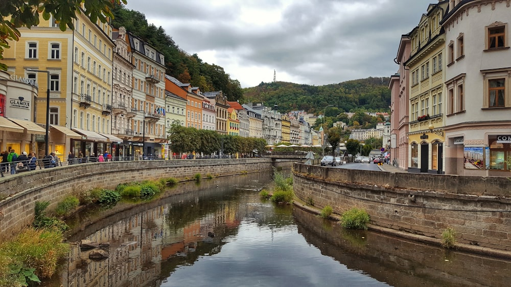 brown and white concrete building beside river under white clouds during daytime