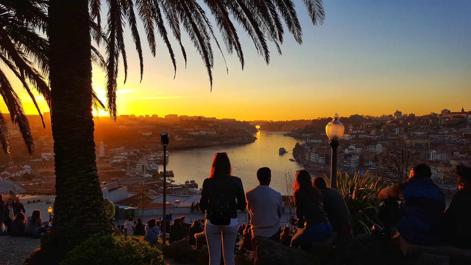 Couple sitting on a bench by the Douro River at sunset in Porto