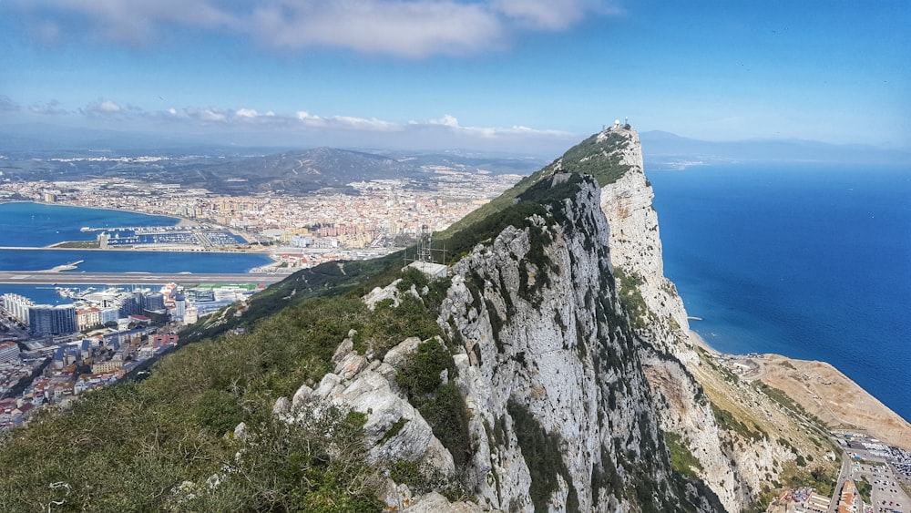 Montagna rocciosa grigia e verde vicino allo specchio d'acqua durante il giorno