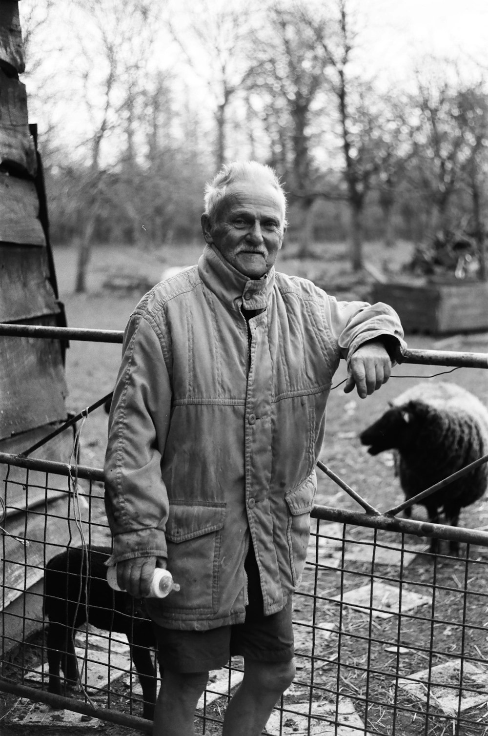 man in gray button up jacket standing beside black short coated dog