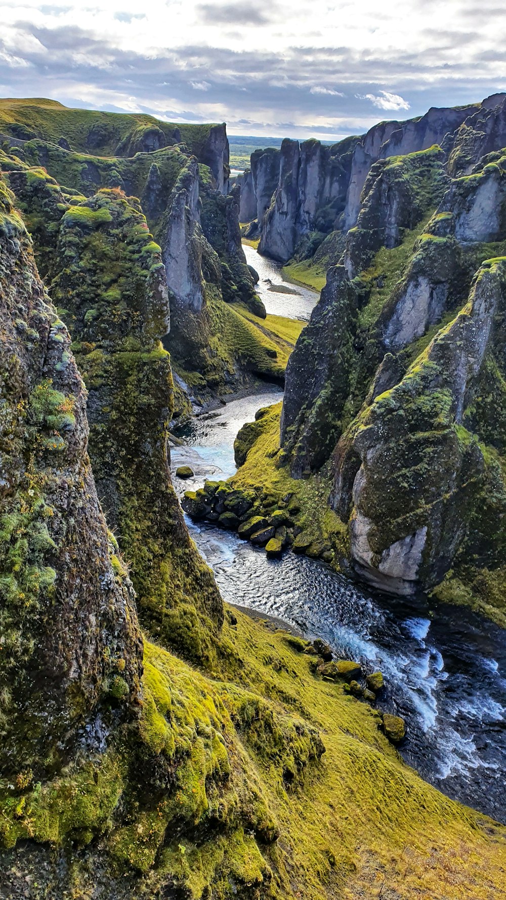 green and gray rocky mountain beside river during daytime