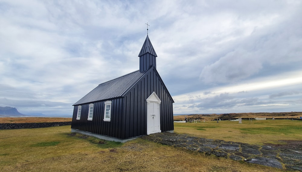 white and gray church on green grass field under white clouds during daytime