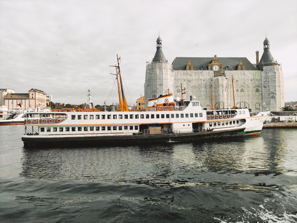 white and brown ship on sea near brown concrete building under white clouds during daytime