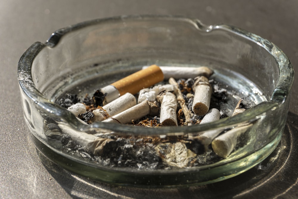 cigarette butts on clear glass ashtray