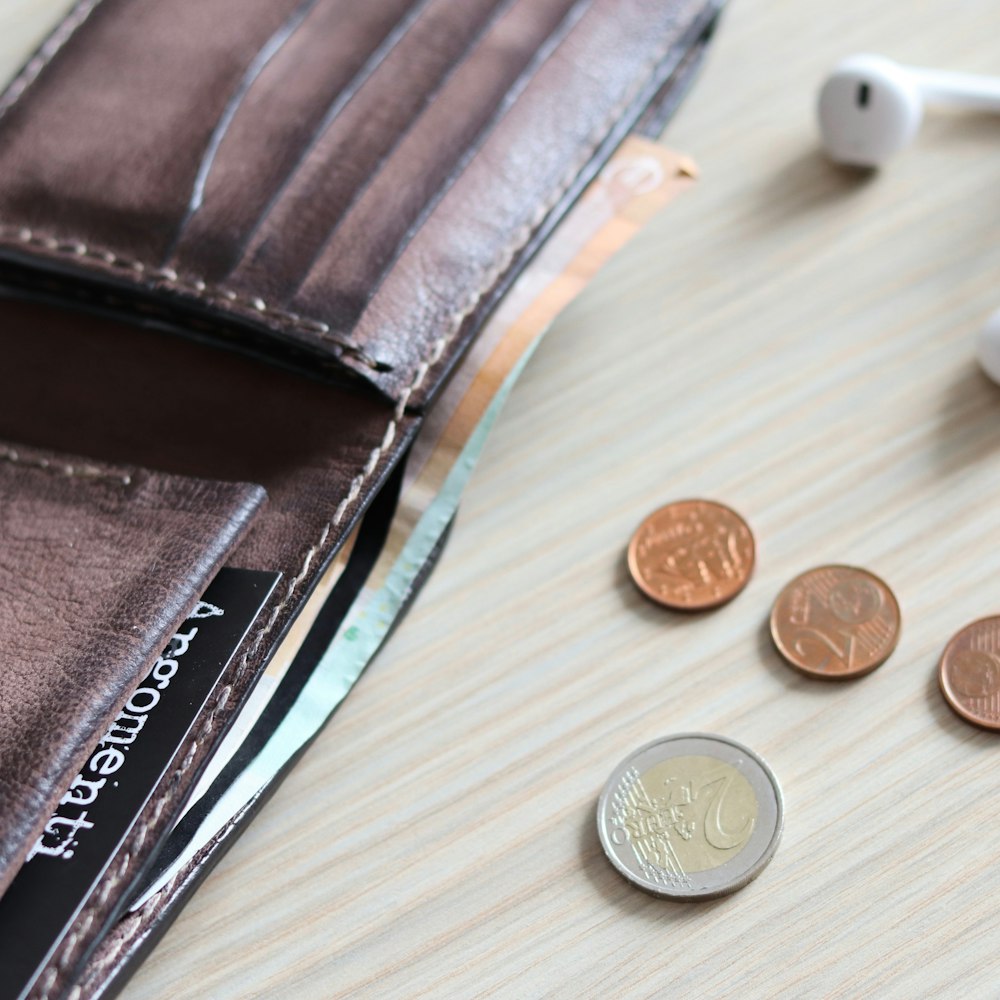 silver round coins beside brown leather wallet
