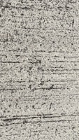 A close-up view of textured concrete with visible lines and small pebbles embedded in the surface.