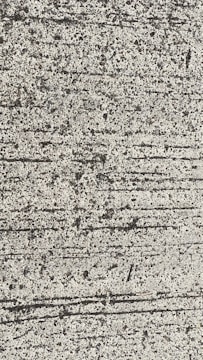 A close-up view of textured concrete with visible lines and small pebbles embedded in the surface.