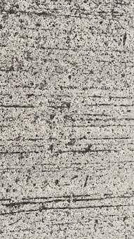 A close-up view of textured concrete with visible lines and small pebbles embedded in the surface.