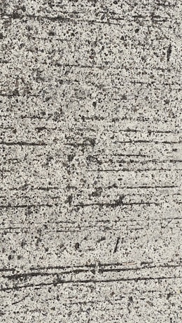 A close-up view of textured concrete with visible lines and small pebbles embedded in the surface.