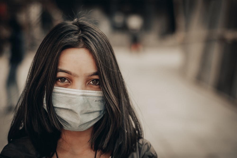 woman in black and white shirt covering face with white face mask