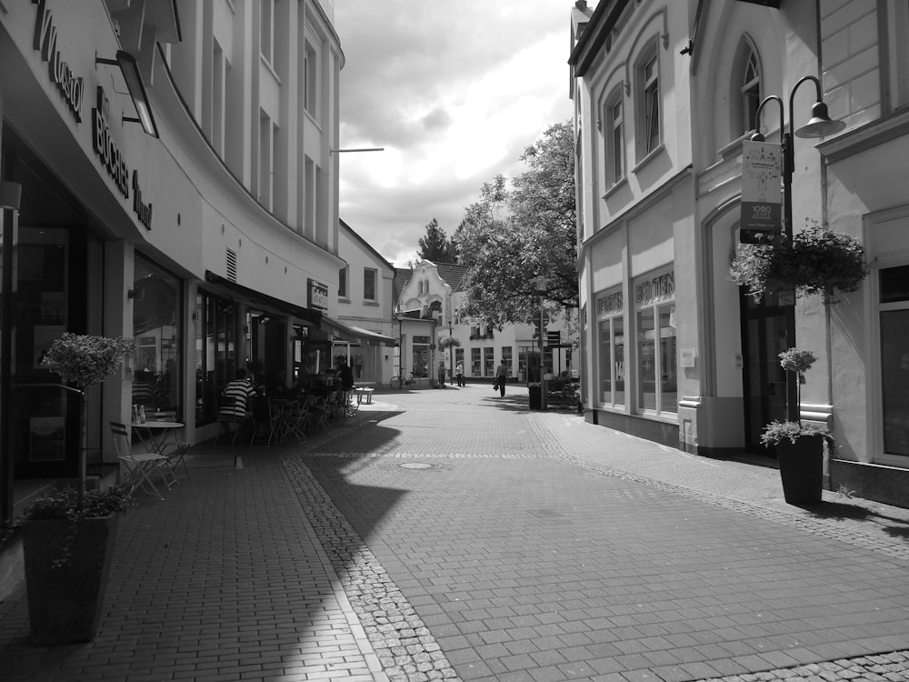 grayscale photo of people walking on sidewalk near buildings