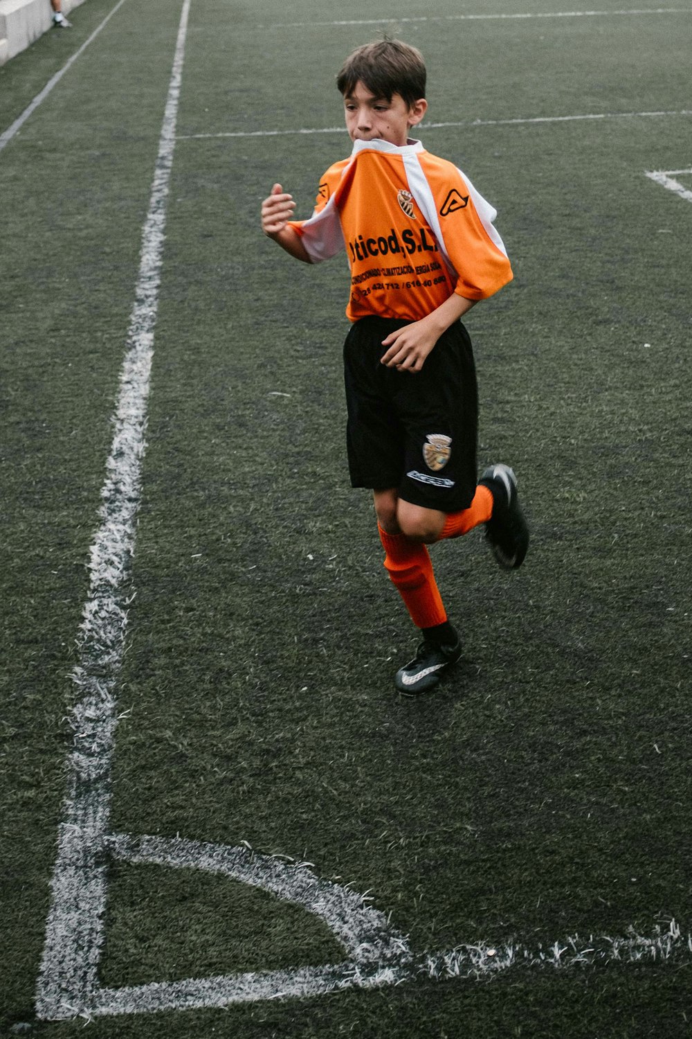 man in orange jersey shirt and black shorts running on gray asphalt road during daytime