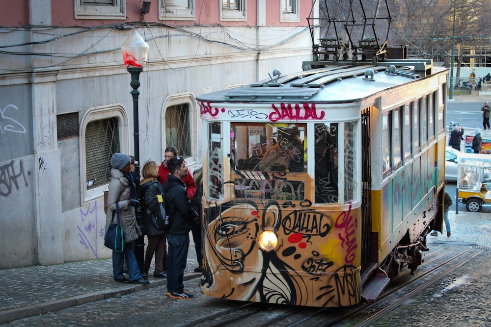 people standing beside yellow and white tram during daytime