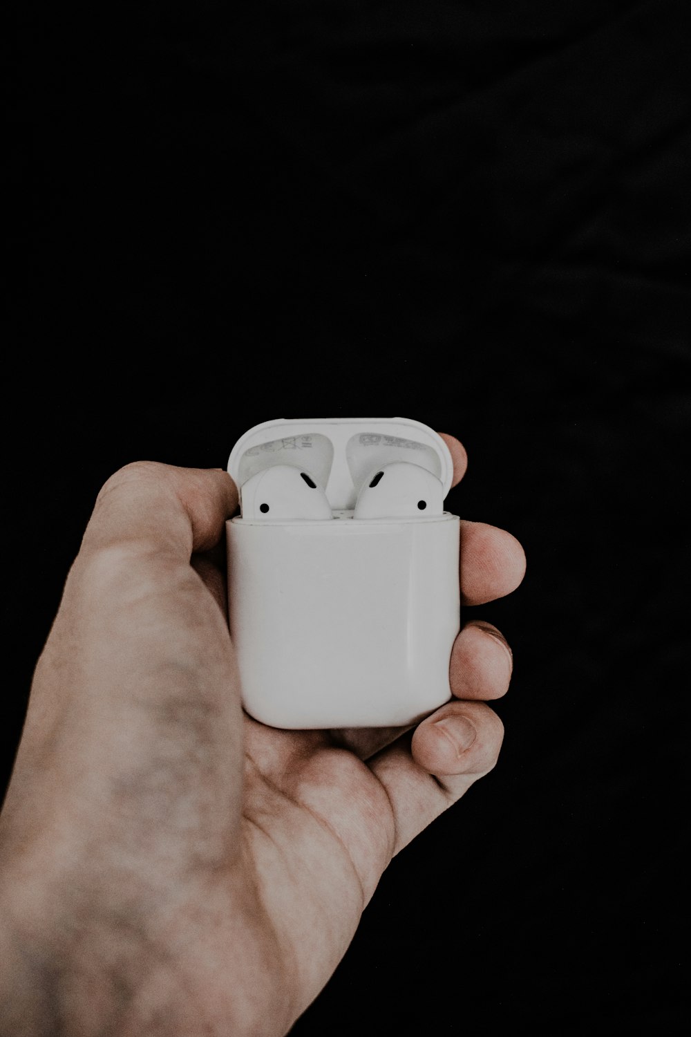 person holding white apple airpods charging case