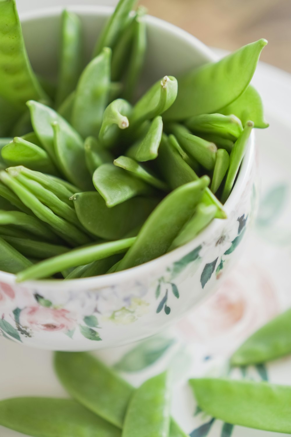 green beans on white and pink floral ceramic bowl