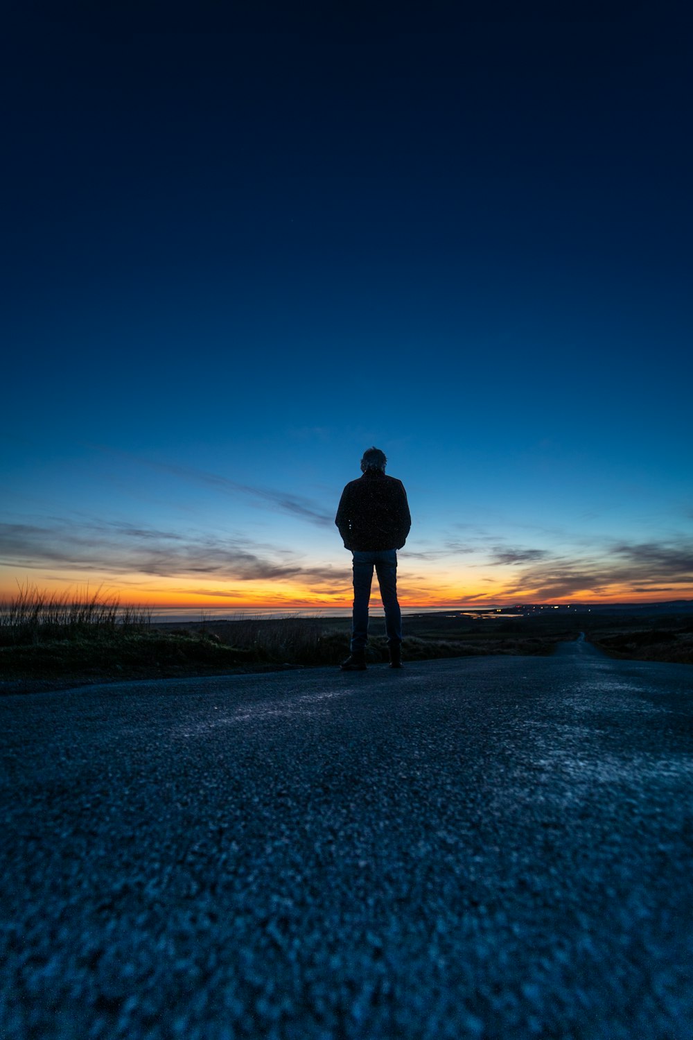 silhouette of man standing on snow covered ground during sunset