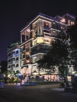 Nighttime shot of a completed multi-story building illuminated in an urban setting.