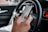 A smiling driver using a smartphone inside a car.