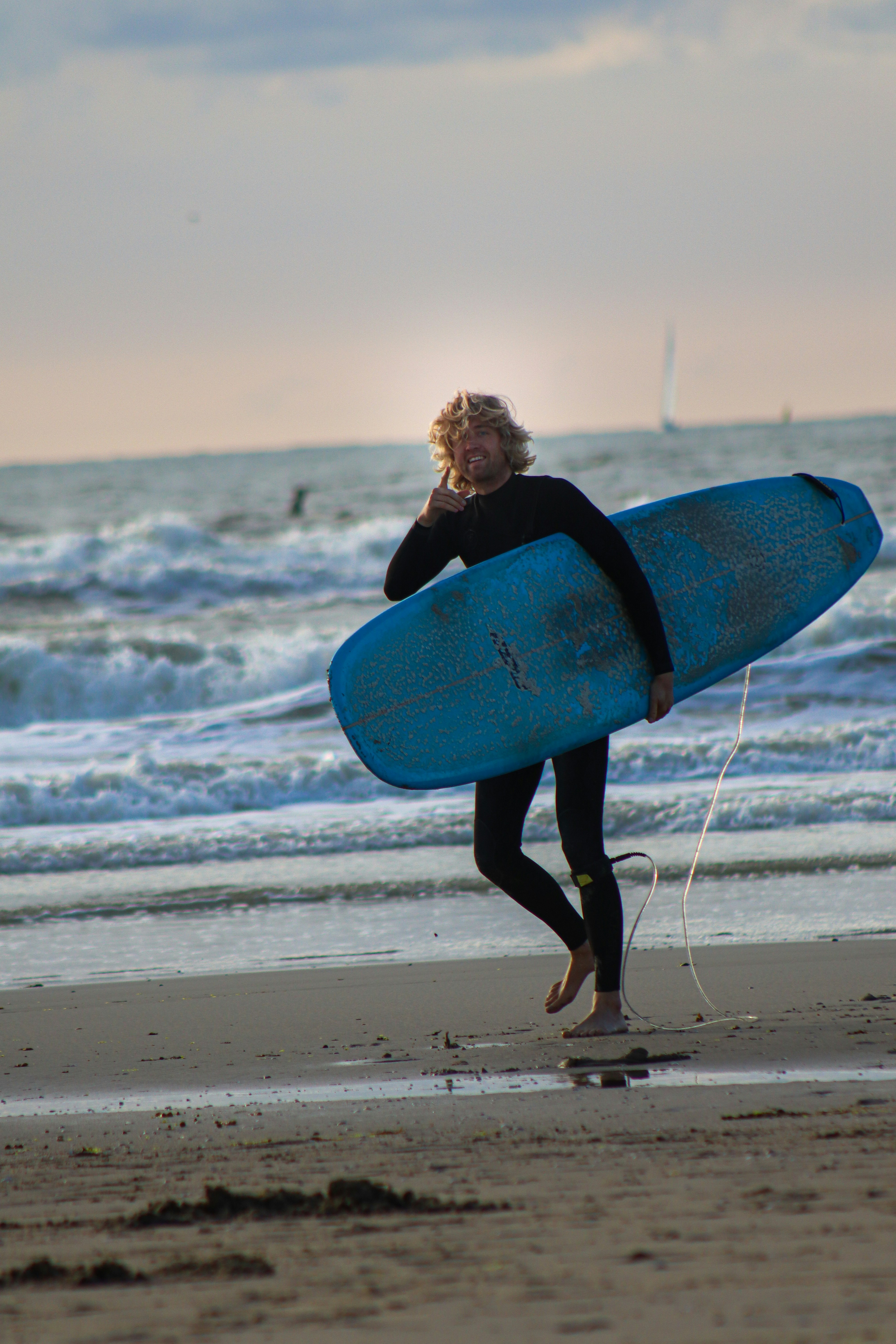 Frau in schwarzem Langarmshirt mit blauem Surfbrett am Strand tagsüber