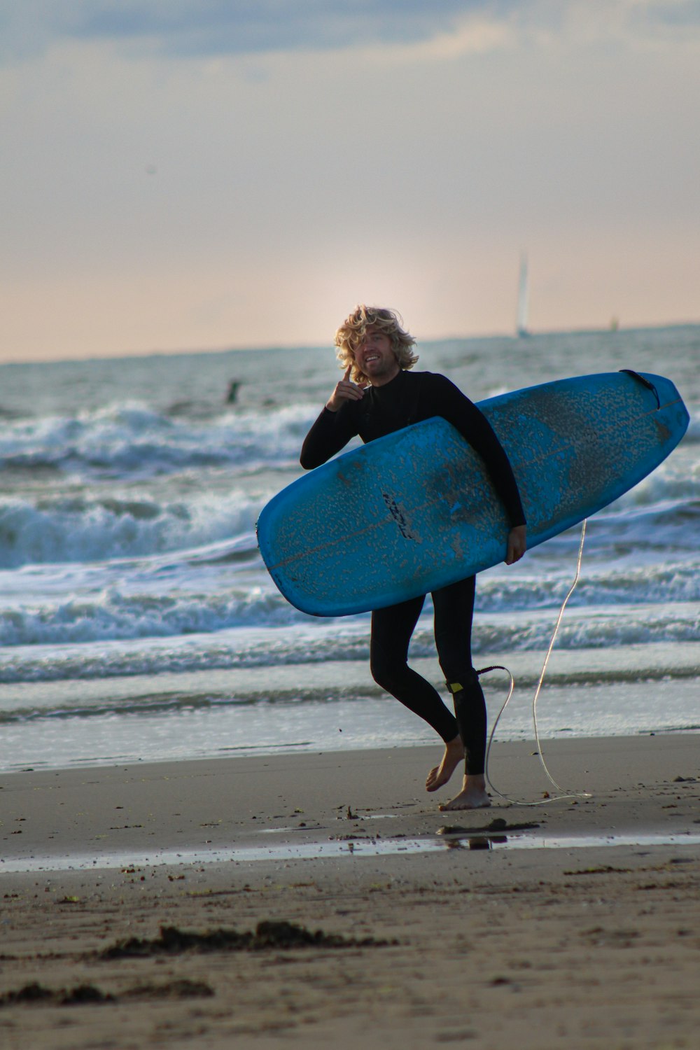 woman in black long sleeve shirt holding blue surfboard on beach during daytime