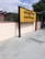 A yellow and black signboard prominently displays the name 'ABUROAD' in both Hindi and English, along with additional text in red below. The sign is positioned on a platform with a tiled floor. Greenery is visible in the background along with a blue sky partially covered by clouds.