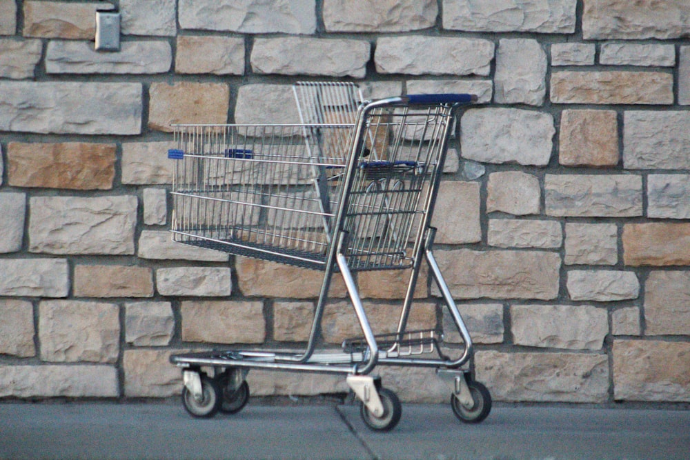 gray shopping cart on gray brick wall