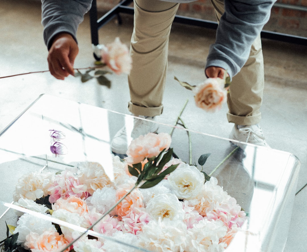 person in white long sleeve shirt holding white and pink flower bouquet